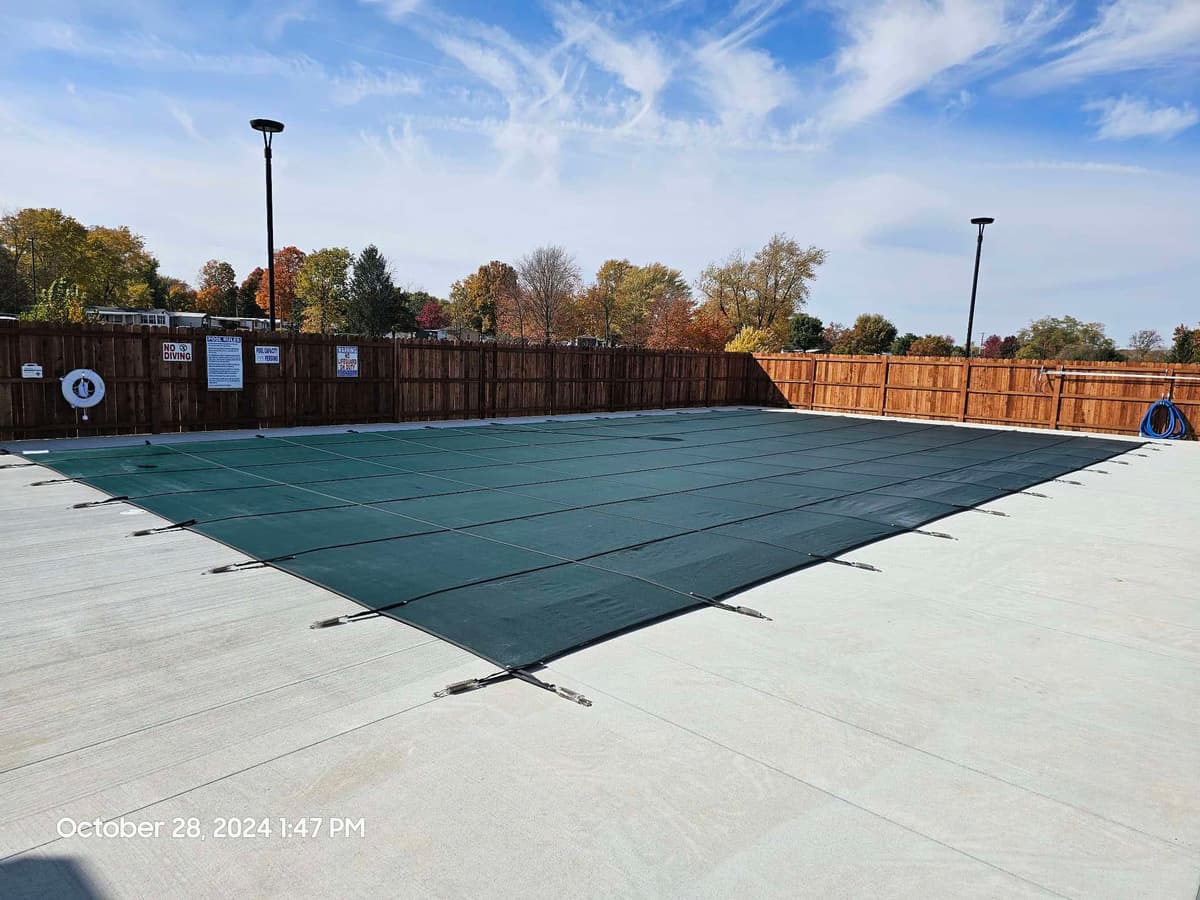 Commercial pool closed for winter under a green mesh safety cover