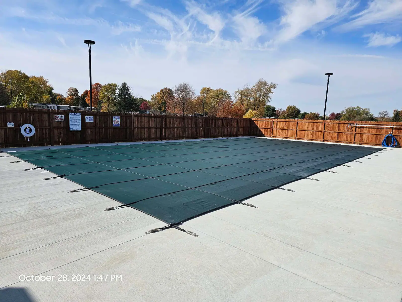 Commercial pool closed for winter under a green mesh safety cover