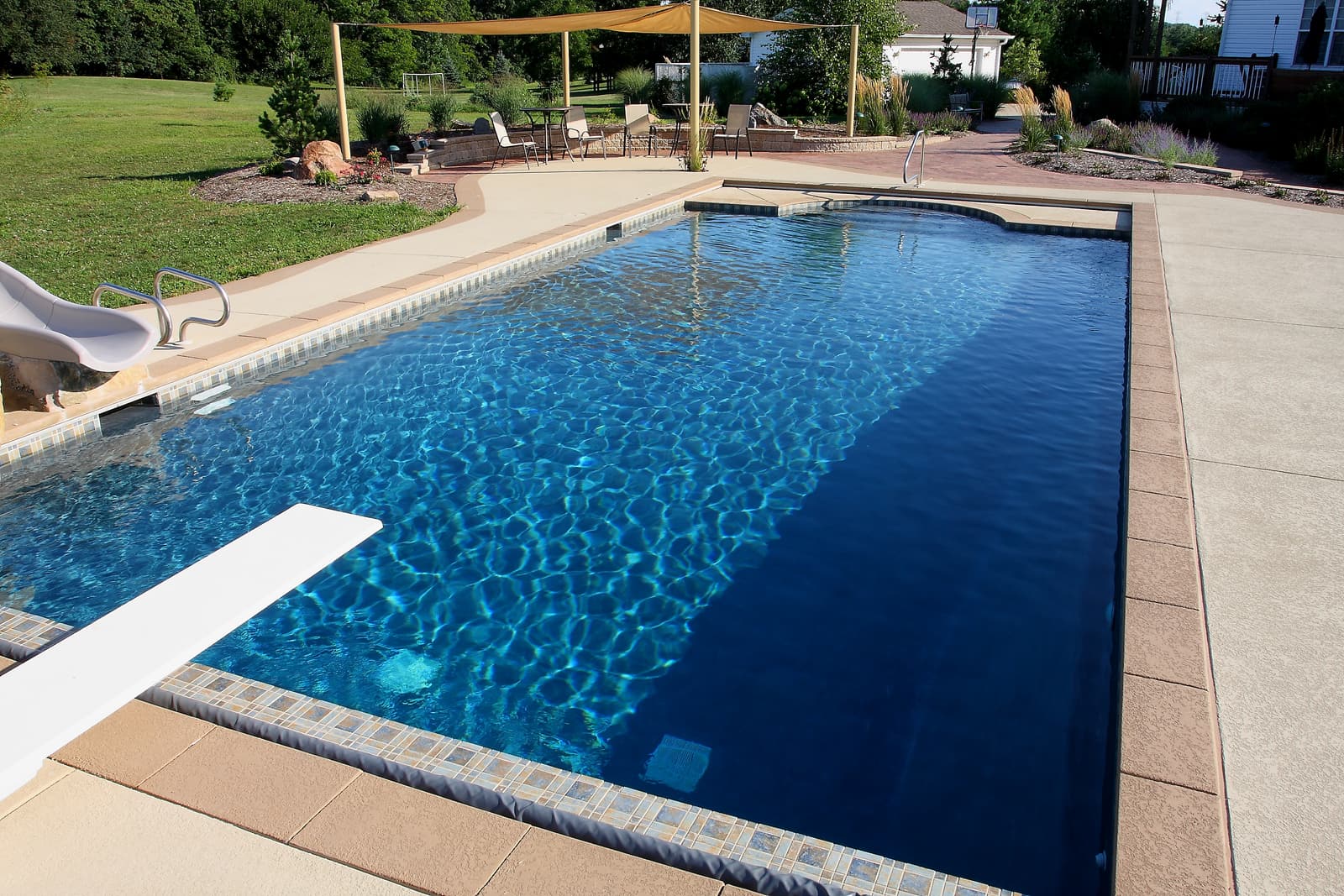 Deep blue gunite pool with diving board and decorative tile band
