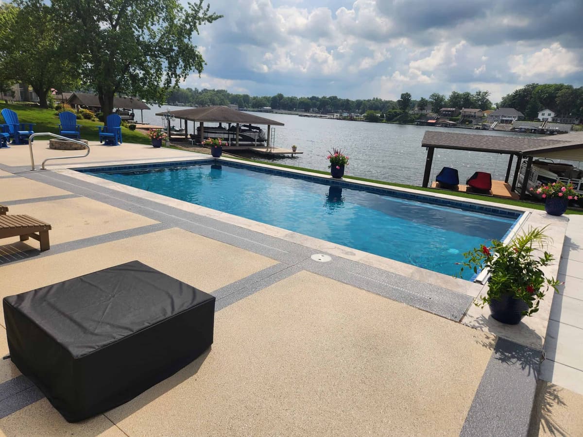 Rectangular pool with a lounge area overlooking a lake and boat docks
