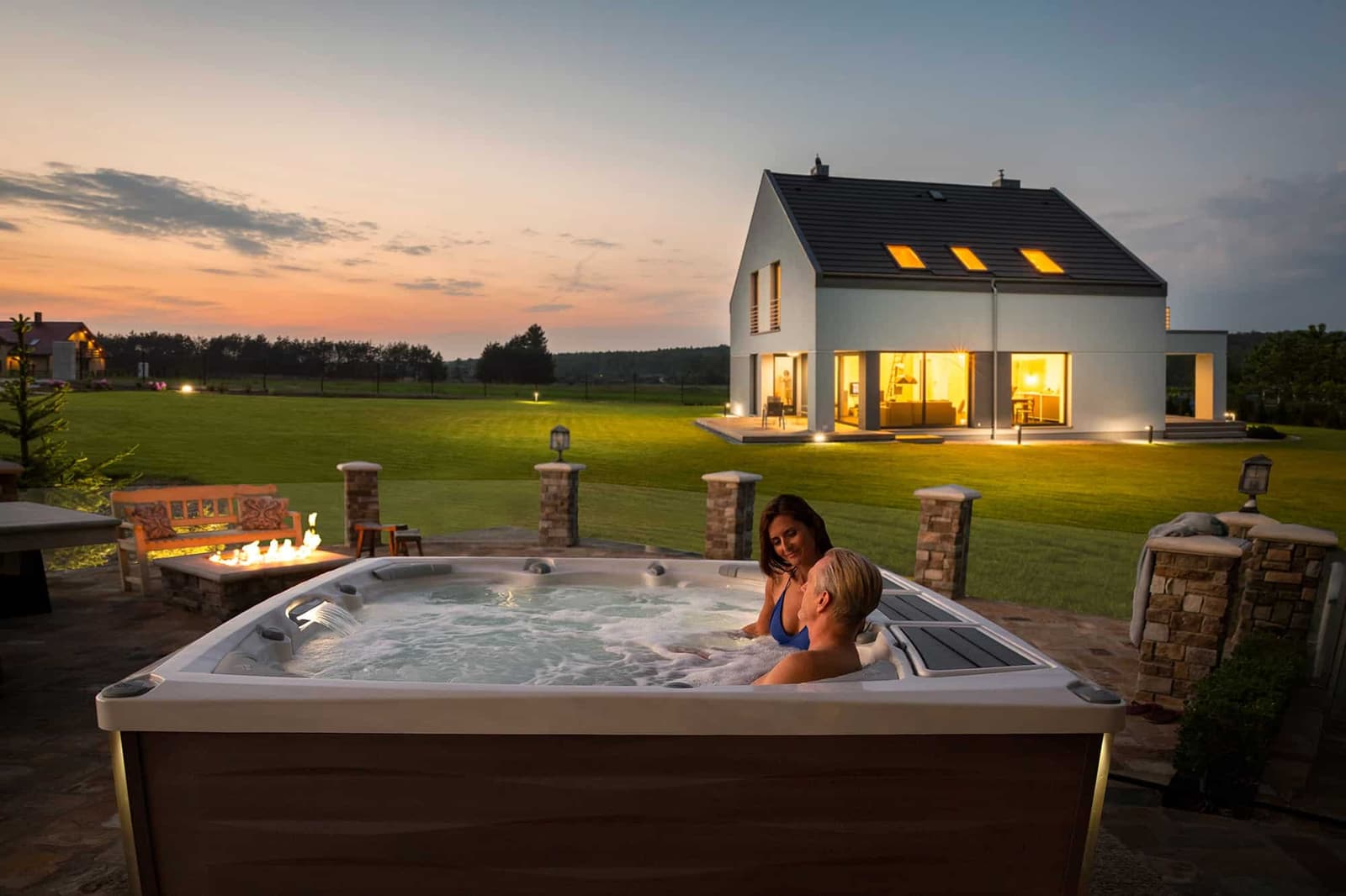 Couple relaxing in a Sundance hot tub at sunset