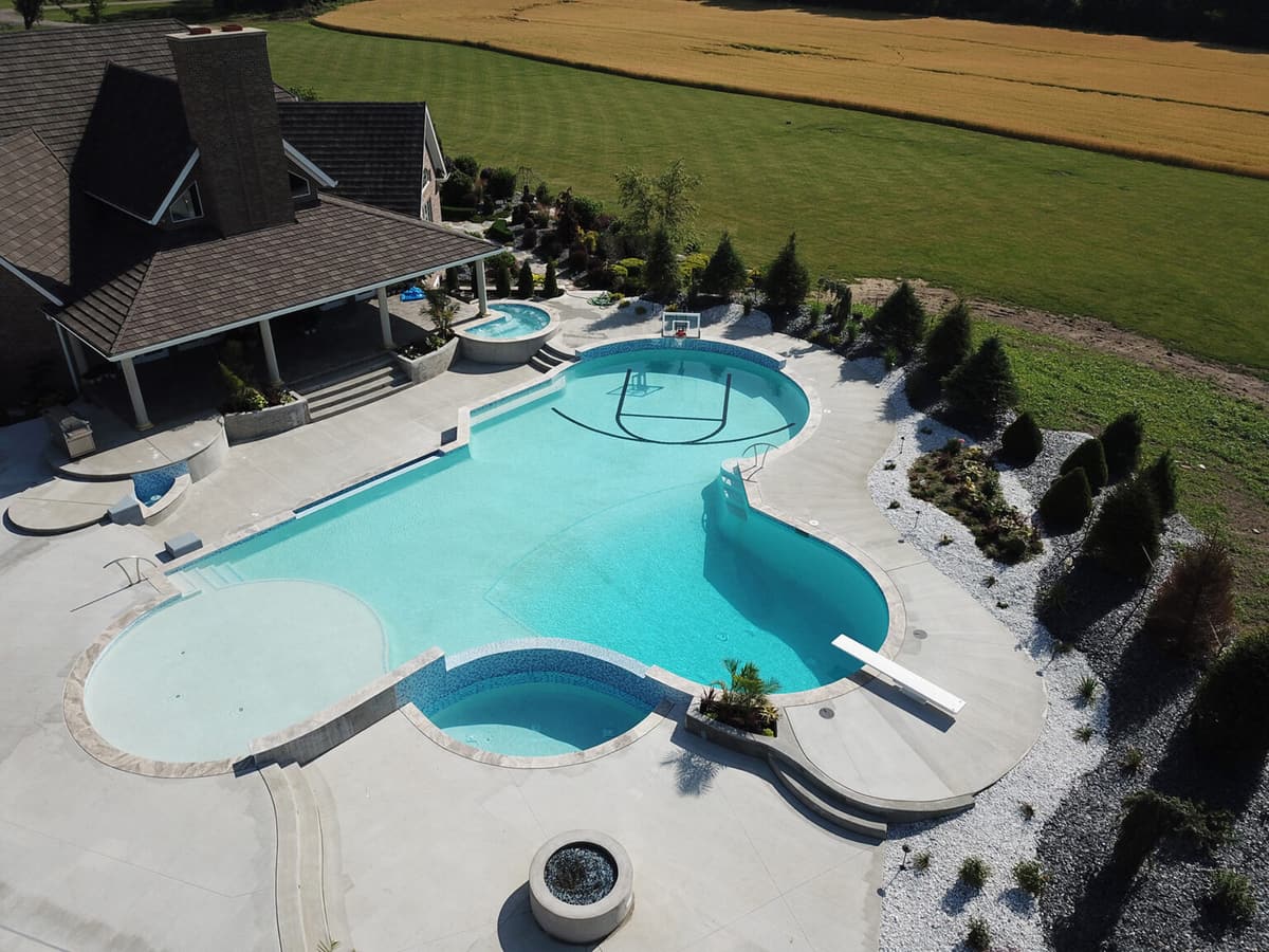 Aerial view of a freeform pool with an attached spa, slide, and covered patio