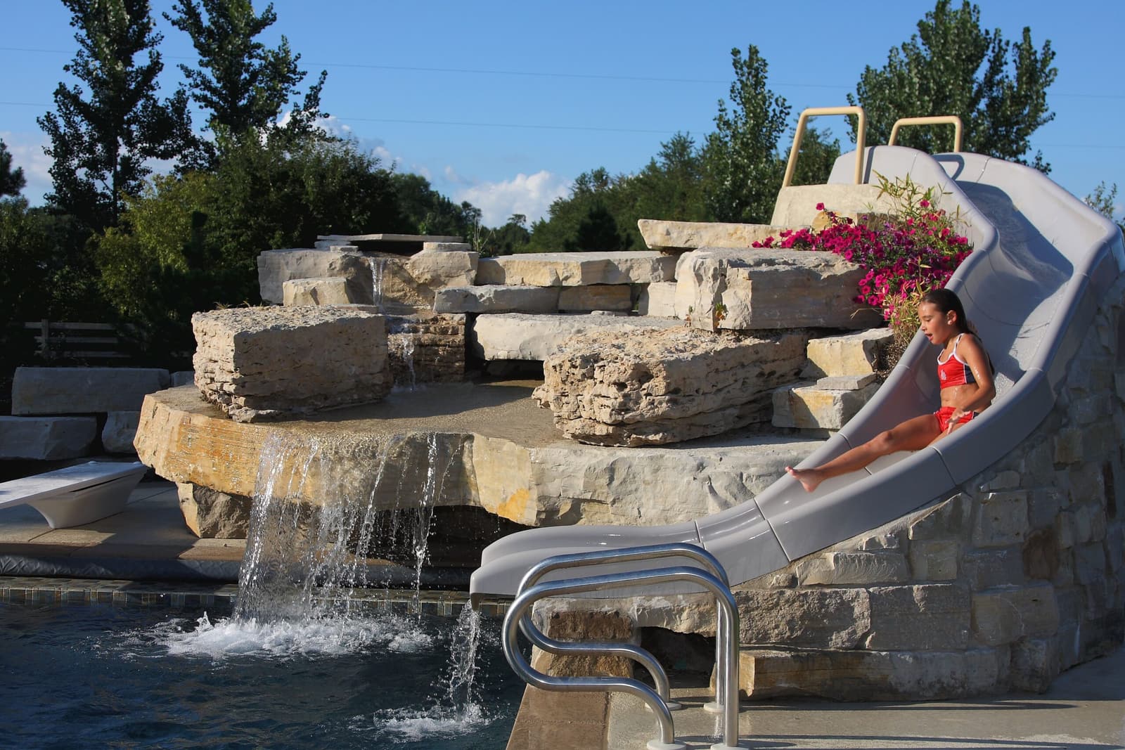 Natural stone waterfall and slide cascading into a pool