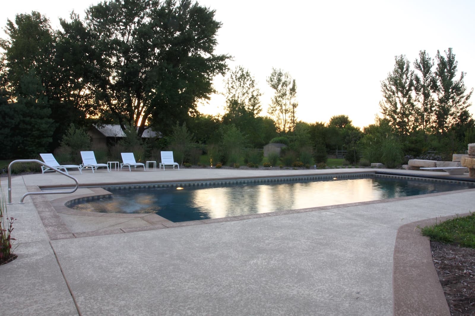 Gunite pool at sunset surrounded by a broad concrete deck