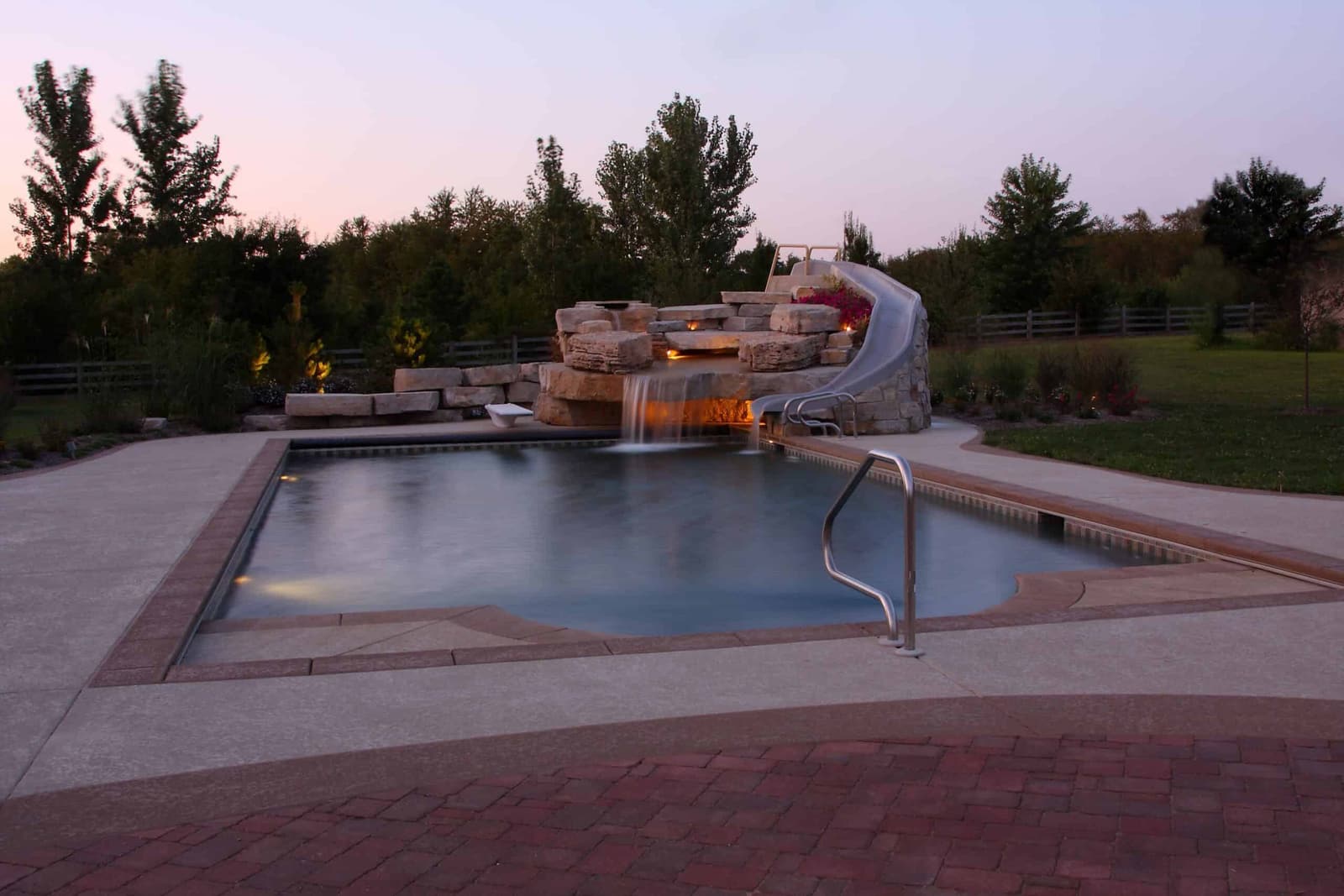 Pool at twilight with a rock waterfall and slide
