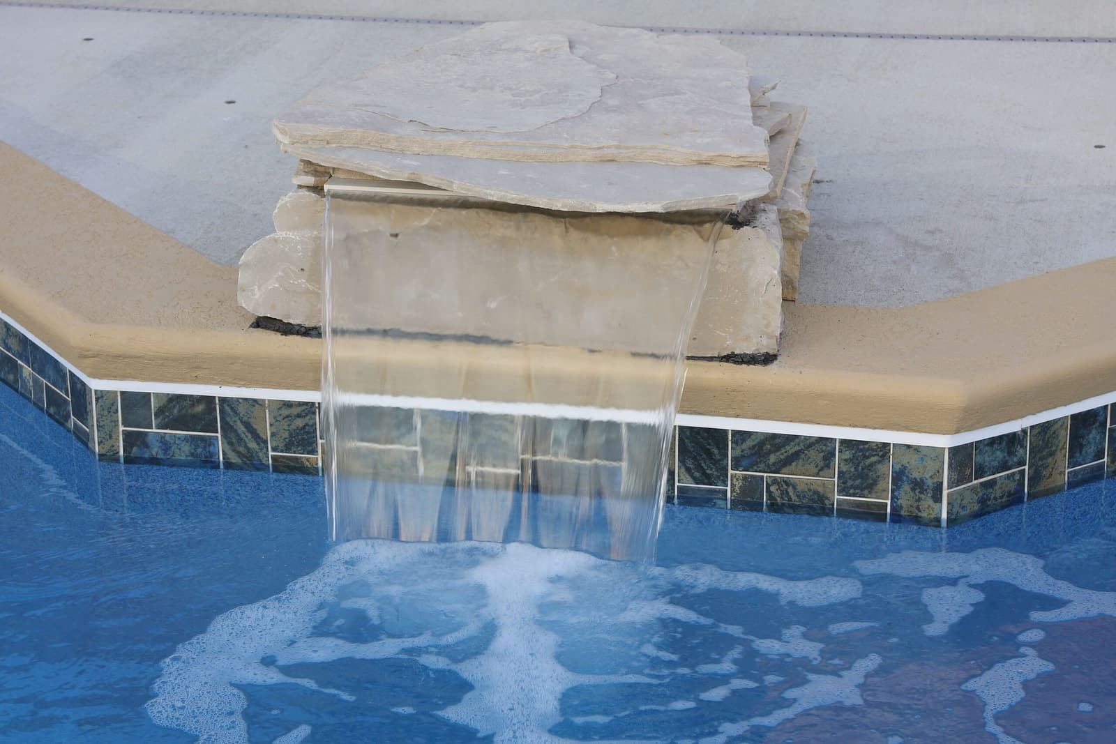 Tiled pool steps with a sheer water descent
