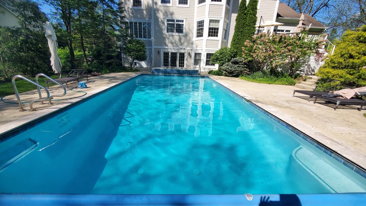 Clear water in a long rectangular pool behind a large home