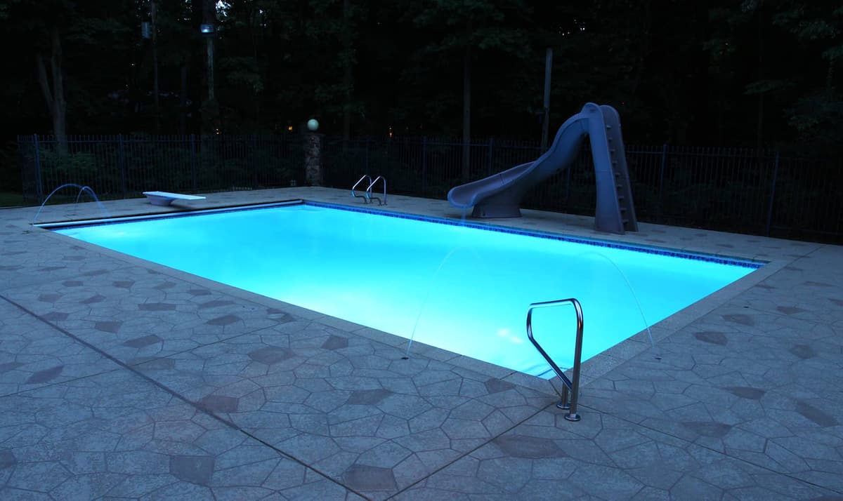 in-ground swimming pool nightime with lights