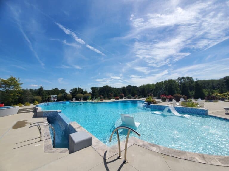 Freeform pool with a waterfall and slide under a bright sky